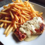 Zartes Hähnchenfilet in cremiger Knoblauchsauce mit goldenen Pommes frites